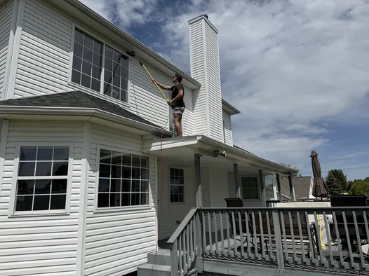 Grime Guyzz technician cleaning upper-story siding in Medina with an extension pole